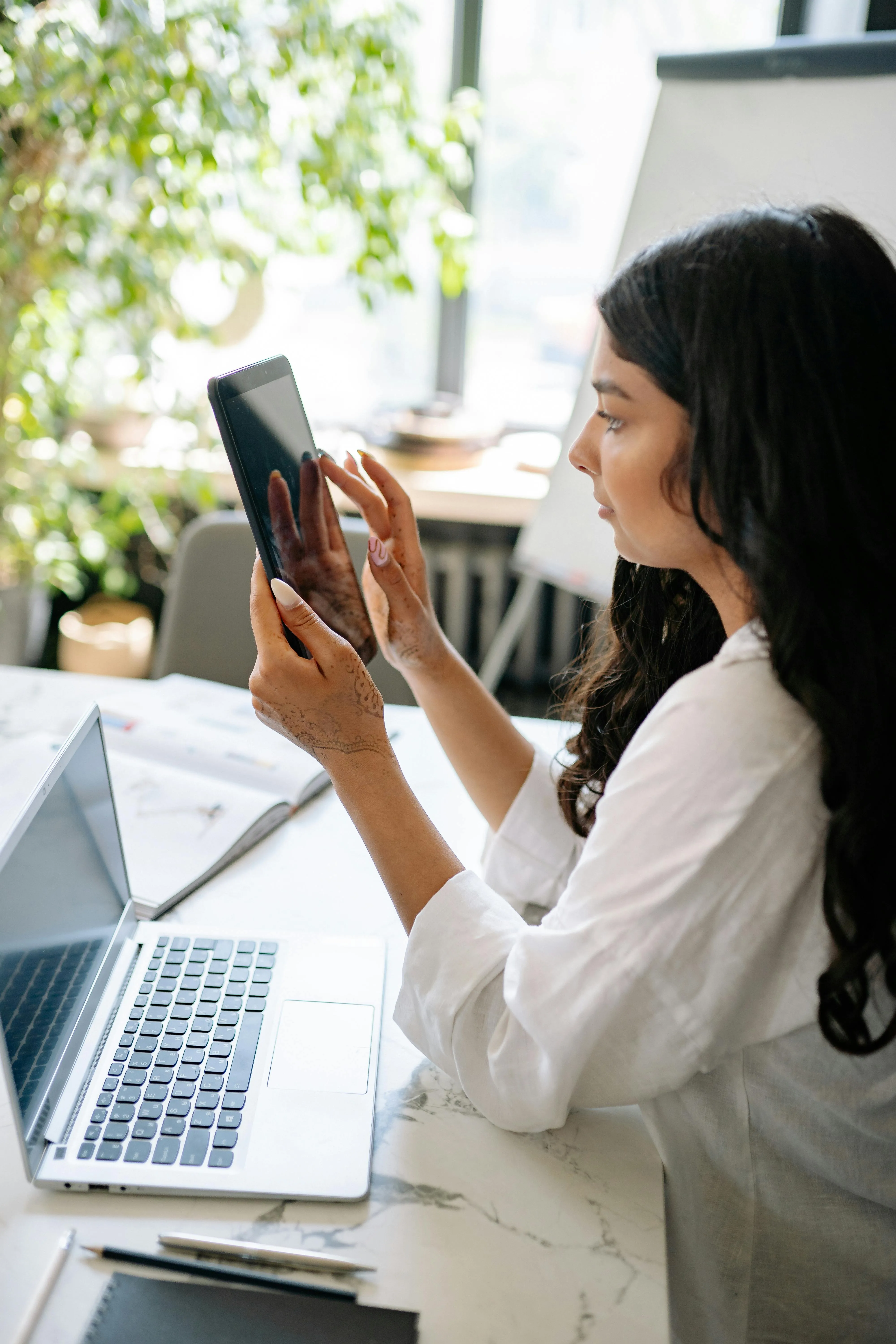 Collega achter een laptop met een tablet in de hand